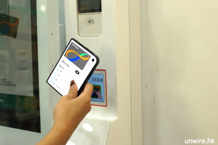 iPhone 14 Pro 開箱 手持 iPhone 14 Pro 在自動售貨機前.