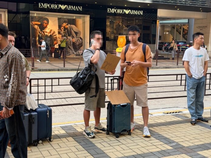 街頭等候手機用戶 兩位年輕人在街上等待手機,旁邊有行李箱.